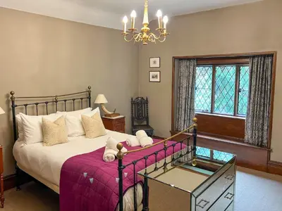 a bedroom with a large bed and a chandelier at Daweswood, Patterdale, characterful with fairy tale garden and fell walks from the door in Patterdale