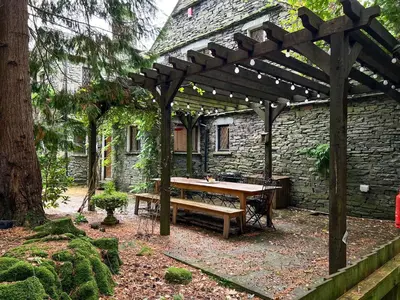 a wooden pergola with a wooden table in a yard at Daweswood, Patterdale, characterful with fairy tale garden and fell walks from the door in Patterdale