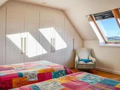 a attic bedroom with a bed and a chair at The Longhouse At Threave in Castle Douglas