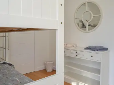 a bedroom with white cabinets and a mirror at The Longhouse At Threave in Castle Douglas
