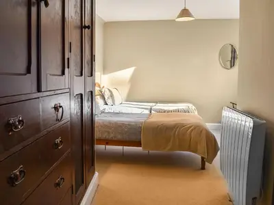 a small bedroom with a bed and a chest of drawers at Tarn Cottage in Grasmere