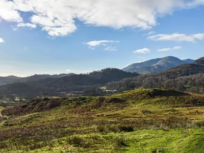 a grassy hill with mountains in the background at Tarn Cottage in Grasmere