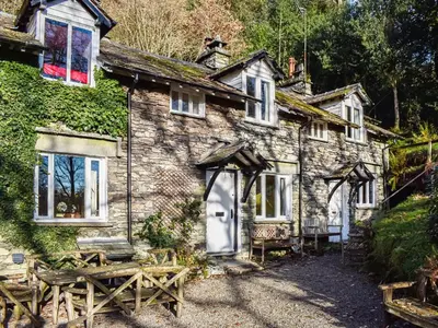 an old stone cottage with a bench in front of it at Tarn Cottage in Grasmere