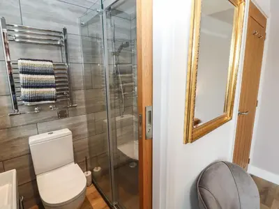 a bathroom with a toilet and a glass shower at Cherry Croft in Wigton
