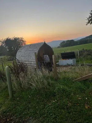 a yurt in a field with the sunset in the background at High Tide Lodge in Gatehouse of Fleet