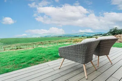 a wicker chair sitting on top of a wooden deck at High Tide Lodge in Gatehouse of Fleet