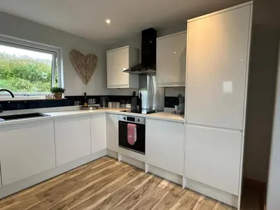 a kitchen with white cabinets and a window at High Tide Lodge in Gatehouse of Fleet