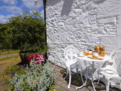 a white table and chairs next to a stone wall at 4 Bed in Moffat 82374 in Moffat