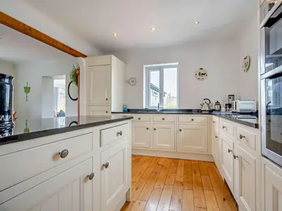 a kitchen with white cabinets and a wooden floor at 4 Bed in Troutbeck nr Ullswater SZ256 in Troutbeck