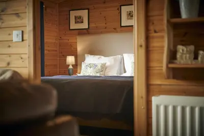 a bedroom with a bed with a wooden wall at Buzzard Lodge with Hot-tub in Carlisle