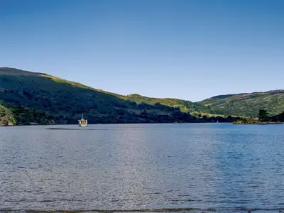a boat on a lake with hills in the background at 2 Bed in Glenridding 85425 in Glenridding