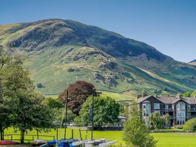 a mountain with a house and boats in a field at 2 Bed in Glenridding 85425 in Glenridding
