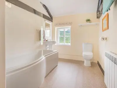 a white bathroom with a tub and a toilet at 3 Bed in Seathwaite SZ107 in Eskdale