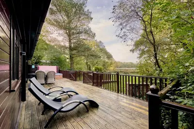 a porch with a bench on a deck with a view at Dunnock Lodge with Hot-tub in Carlisle