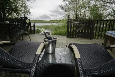 a table with two wine glasses on a patio at Fieldfare Lodge with Hot-tub in Carlisle