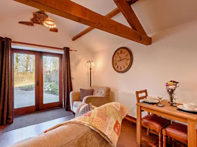 a living room with a table and a clock on the wall at 1 Bed in Allonby 28791 in Allonby