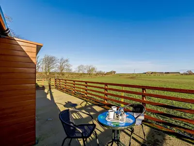 a table and chairs on a porch next to a fence at 1 Bed in Allonby 28791 in Allonby