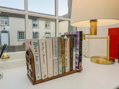 a row of books on a shelf next to a lamp at The Stables in Dumfries