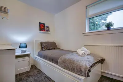 a small bedroom with a bed and a window at Ravenscroft - Coorie Doon in Irvine