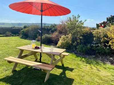 a picnic table with a red umbrella on the grass at 3 Bed in Auldgirth 77430 in Auldgirth