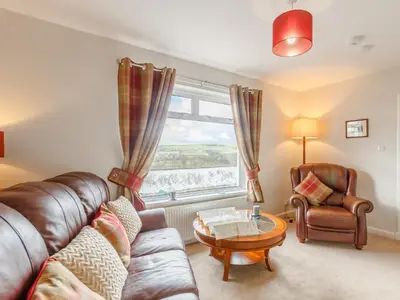 a living room with a couch and a chair and a window at 3 Bed in Auldgirth 77430 in Auldgirth