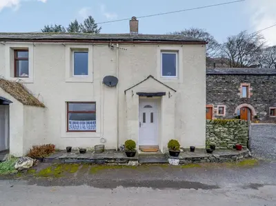 a stone house with a white door and potted plants at 3 Bed in Threlkeld 86613 in Threlkeld