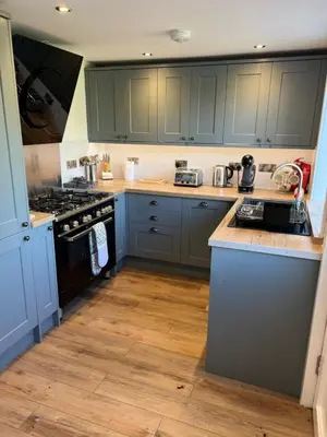 a kitchen with blue cabinets and a stove top oven at The Ship Inn's Mill Cottage - Weavers Way in Gatehouse of Fleet