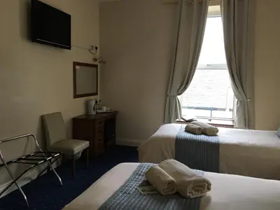 a hotel room with two beds and a window at Cubbon House in Douglas