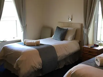 a bedroom with two beds and two windows at Cubbon House in Douglas