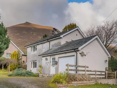 a white house with a garage in front of a mountain at 3 Bed in Threlkeld SZ047 in Threlkeld