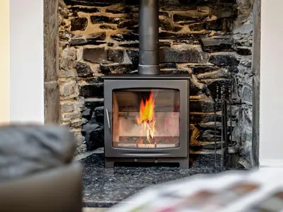 a stone fireplace with a fire in it at 1 Bed in Rosthwaite 86395 in Rosthwaite