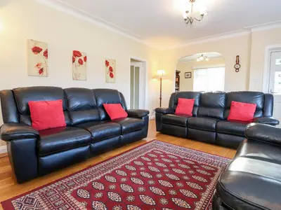 a living room with two leather couches and a rug at Rainbow End in Ambleside