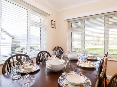 a dining room with a table and chairs and windows at Rainbow End in Ambleside