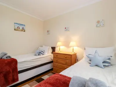 a bedroom with two beds and a night stand with a lamp at Rainbow End in Ambleside