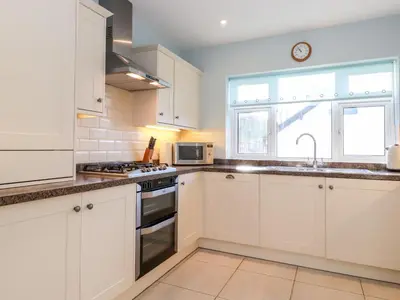 a kitchen with white cabinets and a sink and a window at Rainbow End in Ambleside