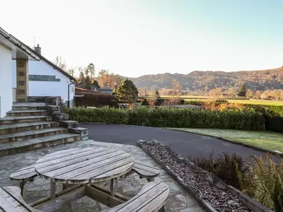 a wooden picnic table sitting in front of a building at Rainbow End in Ambleside