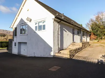 a white house with a garage and stairs at Rainbow End in Ambleside