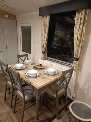 a dining room table with chairs and plates and a window at Hillingworth's Hot Tub Retreat - Lochmaben in Dumfries