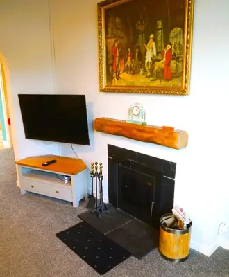 a living room with a tv and a fireplace at Tom's Place in Kirkcudbright