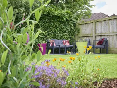 a garden with two chairs and flowers in a yard at 2 Bed in Cockermouth SZ282 in Cockermouth