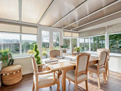 a dining room with a table and chairs and windows at 3 Bed in Cockermouth 82438 in Dearham