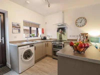 a kitchen with a washing machine and a bowl of fruit on a counter at Hollys Hideaway in Castle Douglas
