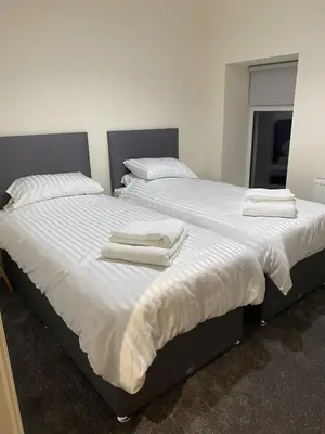 two beds in a bedroom with white sheets and pillows at Craigielea Cottage in Newton Stewart