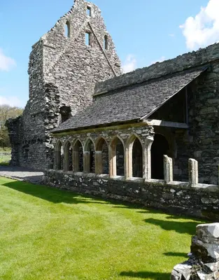 an old stone church with a tower and green grass at Craigielea Cottage in Newton Stewart