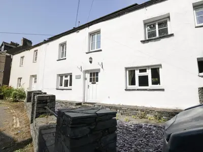 a white house with black stones in front of it at Taylor's Cottage in Keswick
