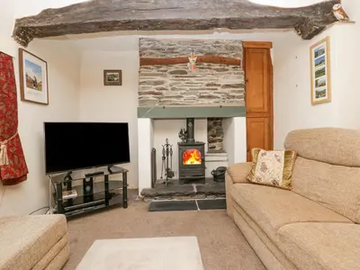 a living room with a fireplace and a tv at Taylor's Cottage in Keswick