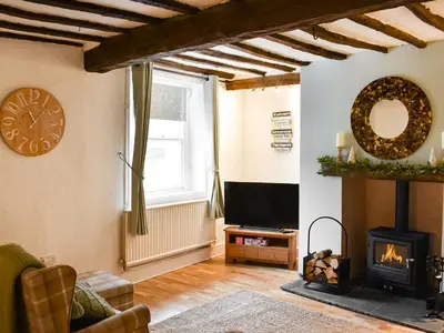a living room with a fireplace and a tv at Daffodil Cottage in Cockermouth