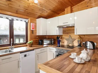 a kitchen with white cabinets and a wooden ceiling at Latrigg Lodge in Keswick