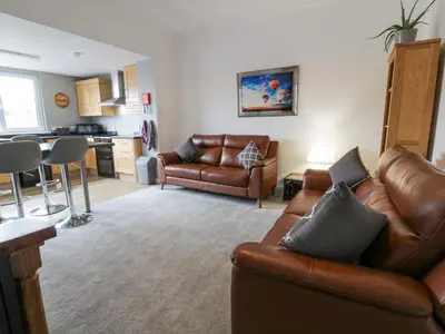 a living room with a leather couch and a kitchen at Little Ireland in Stranraer