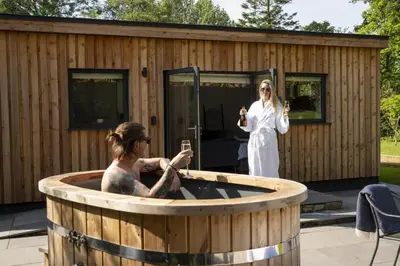 a woman standing next to a jacuzzi tub at Shepherds Retreat Hutton John in a walled garden in a rural setting only 10 minutes for Lake Ullswater in Penruddock